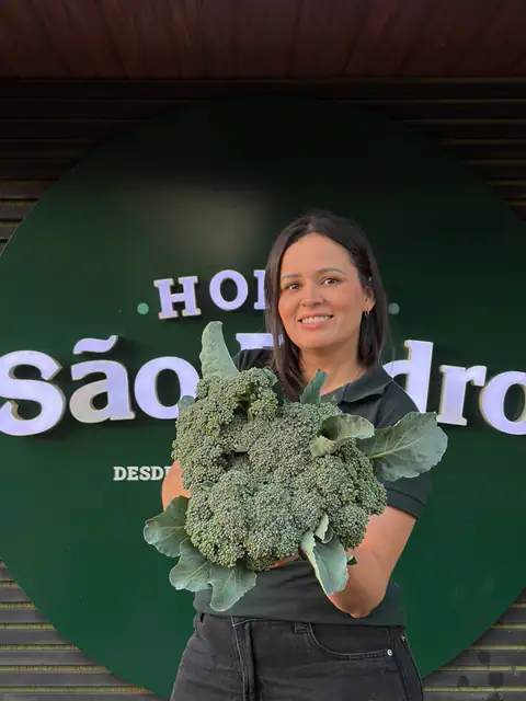 Atendente da Horta São Pedro segurando brócolis